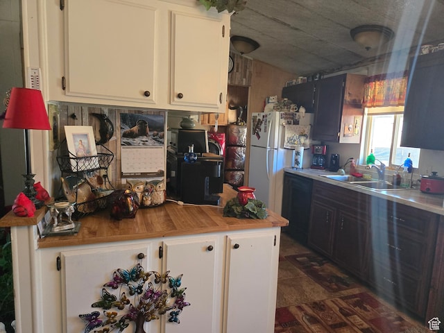 kitchen with white cabinetry, a sink, and freestanding refrigerator