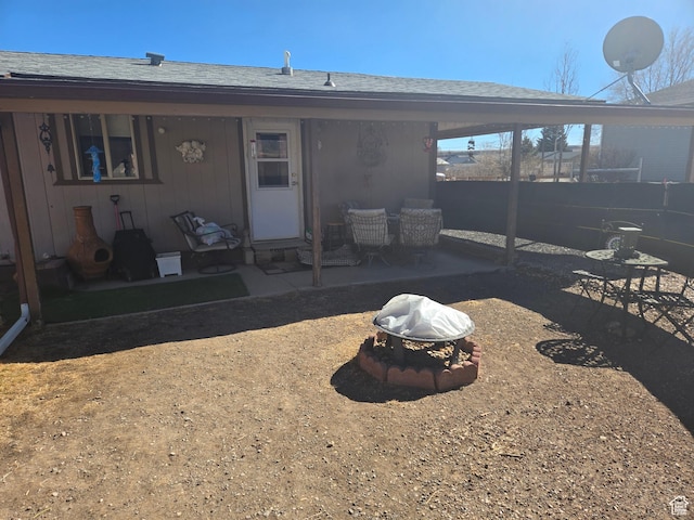 rear view of property with fence, a fire pit, a shingled roof, and a patio