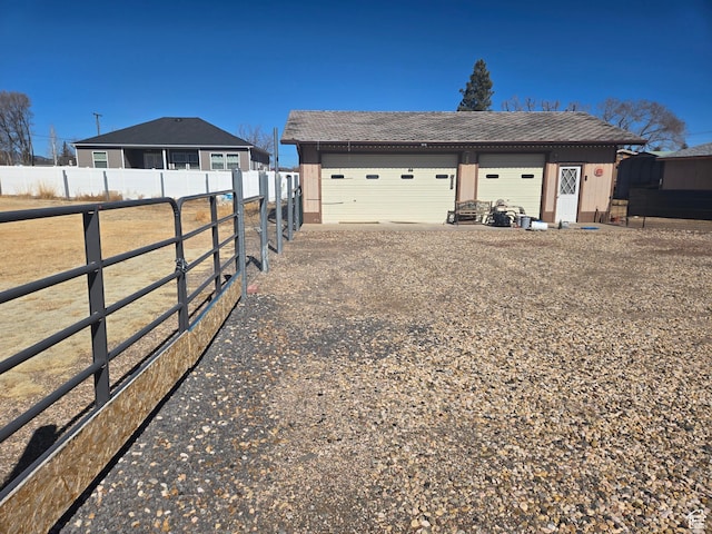 view of yard featuring an outdoor structure, driveway, a garage, and fence