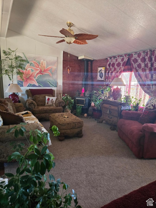 carpeted living area with a textured ceiling, vaulted ceiling, a wood stove, and a ceiling fan