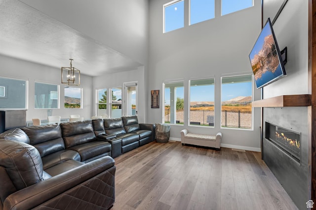 3032 W Cramden Dr, Lehi, UT 84043 - living area featuring a tiled fireplace, a chandelier, wood-type flooring, baseboards, and a towering ceiling