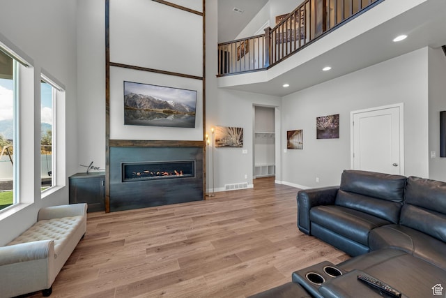 3032 W Cramden Dr, Lehi, UT 84043 - living room with visible vents, baseboards, wood finished floors, a glass covered fireplace, and a high ceiling