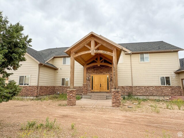 view of front of house featuring a shingled roof and stone siding