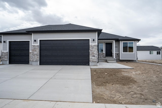 prairie-style house featuring driveway, stone siding, and a garage