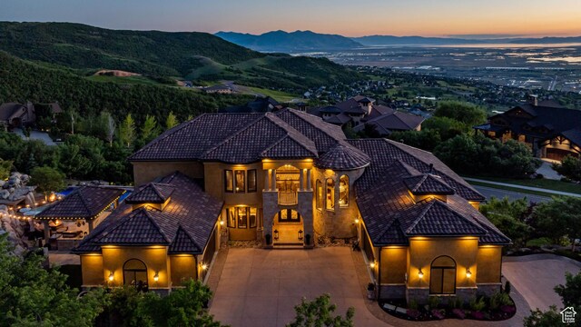 mediterranean / spanish home featuring a tile roof, stucco siding, stone siding, driveway, and a mountain view