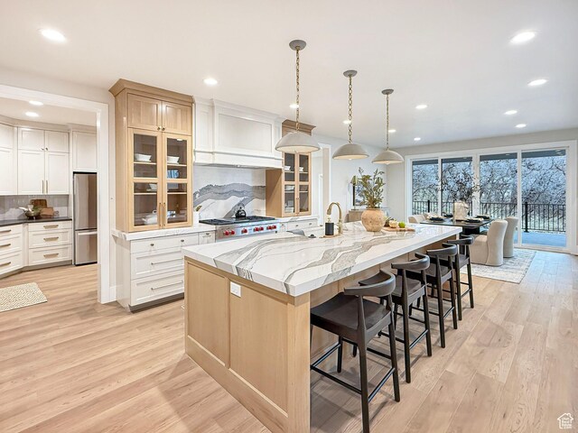 4014 N Dillon Way N, Ogden, UT 84414 - kitchen with a breakfast bar area, a spacious island, freestanding refrigerator, light wood-style flooring, and glass insert cabinets