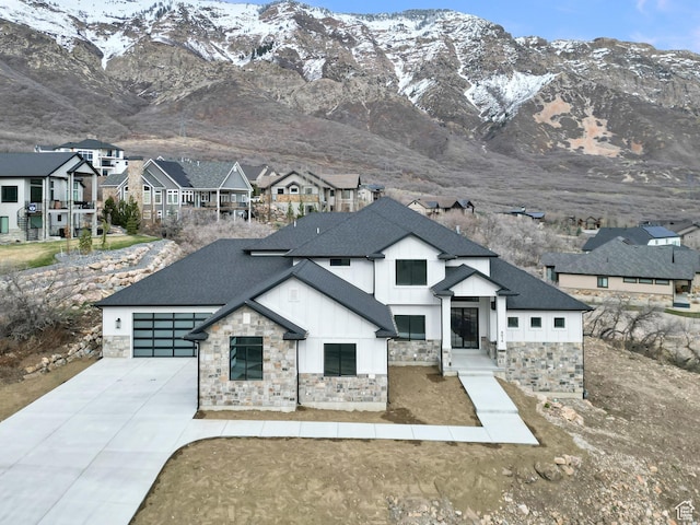 modern inspired farmhouse with roof with shingles, an attached garage, stone siding, board and batten siding, and driveway