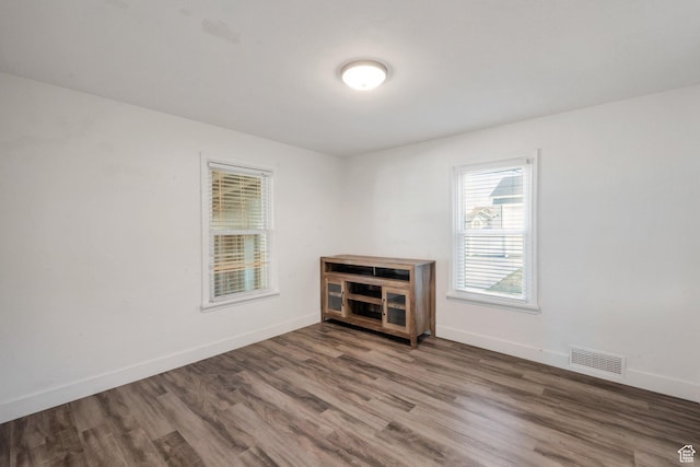 empty room featuring wood finished floors, baseboards, and visible vents