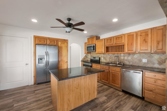 kitchen with a center island, dark wood-type flooring, a sink, dark countertops, and appliances with stainless steel finishes