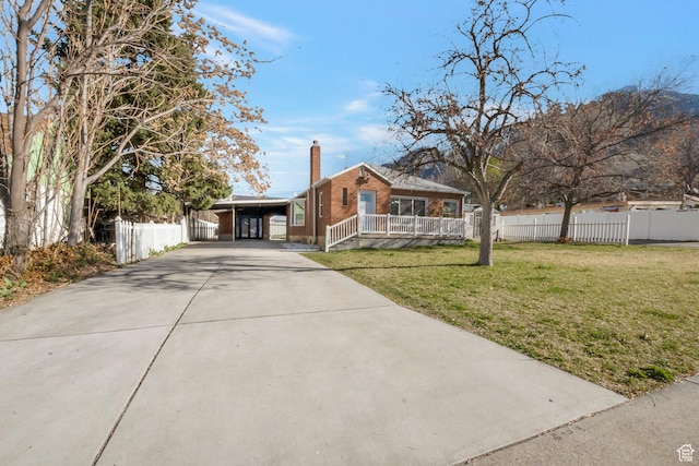 view of front of home featuring driveway, a front yard, a chimney, fence, and brick siding