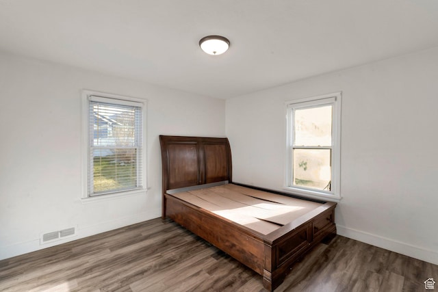 bedroom featuring baseboards, visible vents, and wood finished floors