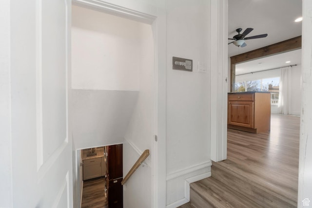 corridor featuring wood finished floors, an upstairs landing, and beam ceiling