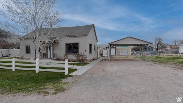 view of front of property featuring an outdoor structure, stucco siding, fence, driveway, and a carport