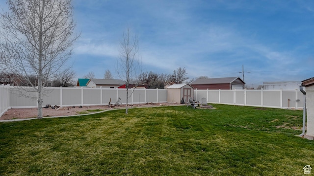 view of yard with a storage unit, an outdoor fire pit, a fenced backyard, and an outdoor structure