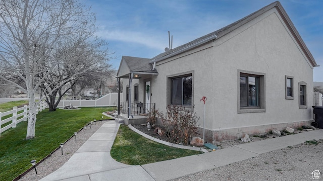 view of home's exterior with stucco siding, fence, and a yard