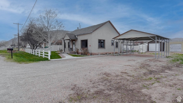 view of front of home featuring an outdoor structure, stucco siding, fence, a front yard, and a garage