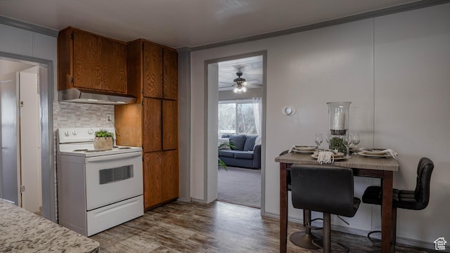 kitchen featuring light countertops, tasteful backsplash, under cabinet range hood, white electric range, and a ceiling fan