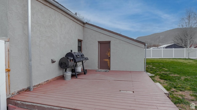 wooden deck featuring a grill, a lawn, fence, and a mountain view