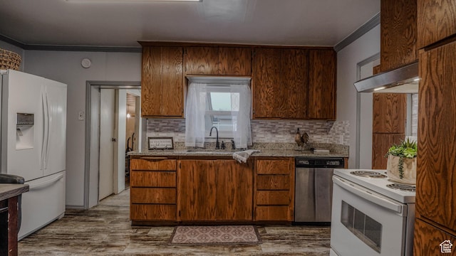 kitchen featuring crown molding, white appliances, tasteful backsplash, under cabinet range hood, and a sink