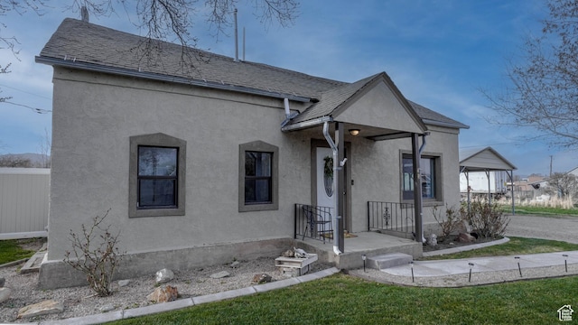 view of front of property featuring a shingled roof, stucco siding, and fence
