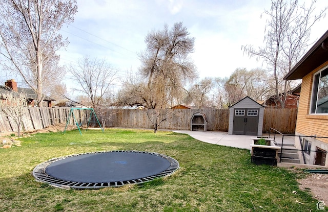 view of yard with a storage unit, a fenced backyard, an outdoor structure, and a playground