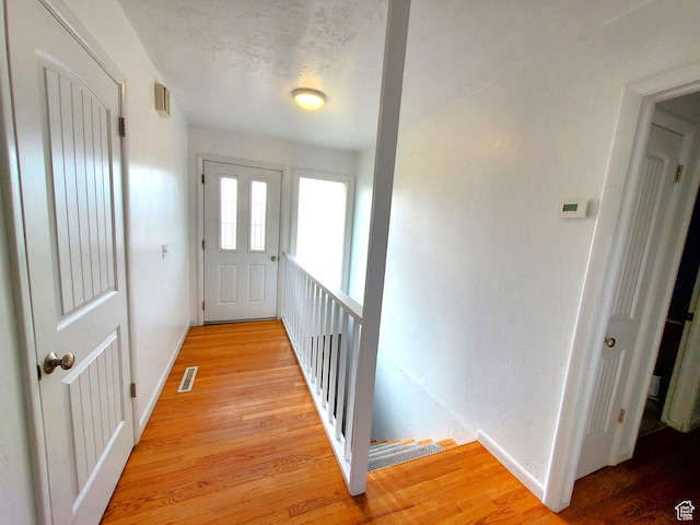 interior space with baseboards, visible vents, light wood-style flooring, and a textured ceiling