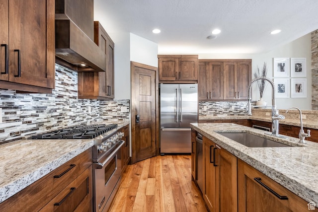 853 W Benjamin Pl, Kamas, UT 84036 - kitchen featuring wall chimney range hood, decorative backsplash, light wood-style flooring, a sink, and high quality appliances