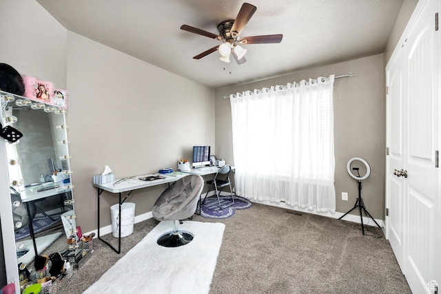carpeted home office featuring baseboards, a textured ceiling, ceiling fan, and visible vents