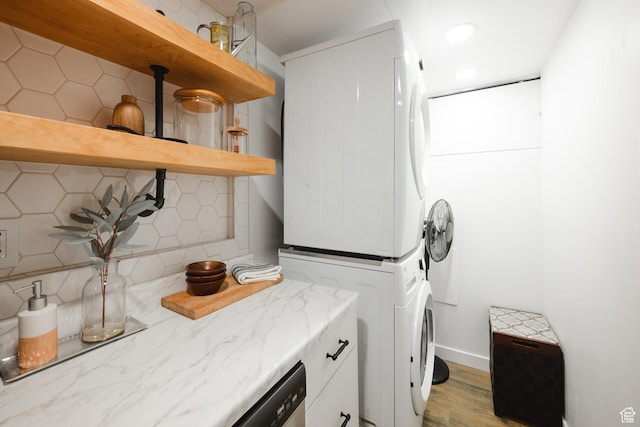 clothes washing area featuring baseboards, laundry area, stacked washer and dryer, recessed lighting, and light wood-style flooring