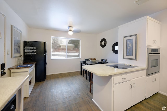 kitchen with dark wood finished floors, a peninsula, white cabinetry, black appliances, and light countertops