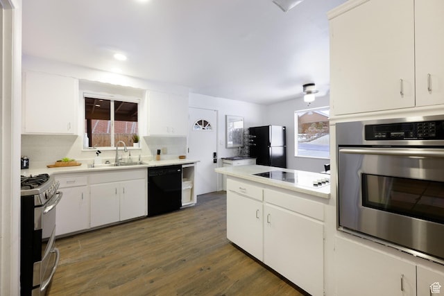 kitchen with a sink, light countertops, black appliances, and wood finished floors