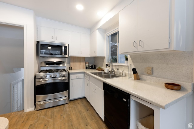 kitchen featuring light countertops, white cabinets, stainless steel appliances, a sink, and wood finished floors