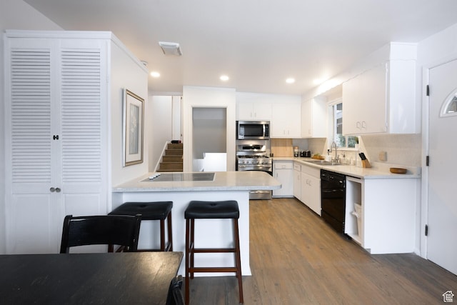 kitchen featuring light countertops, white cabinets, black appliances, a sink, and wood finished floors