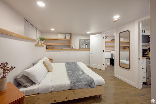 bedroom with recessed lighting, a walk in closet, and wood finished floors