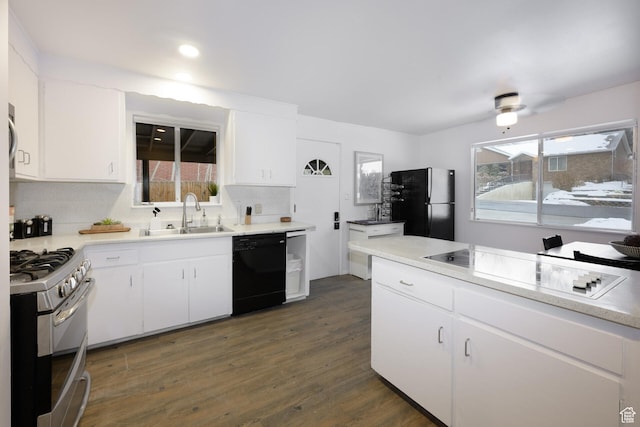 kitchen featuring dark wood-type flooring, white cabinets, black appliances, a sink, and light countertops