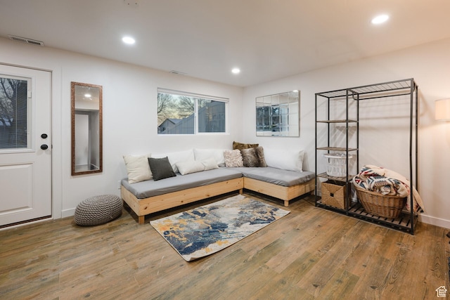 living room with recessed lighting, visible vents, baseboards, and wood finished floors