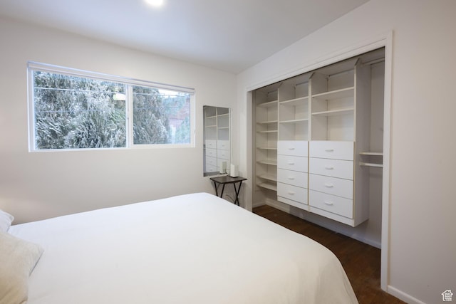 bedroom with dark wood-type flooring, a closet, baseboards, and multiple windows