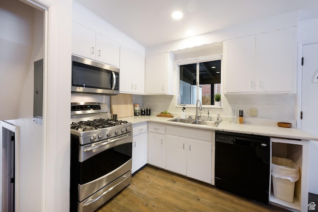 kitchen with white cabinetry, wood finished floors, light countertops, a sink, and stainless steel appliances