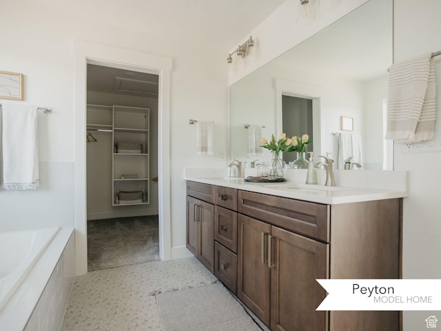 full bath with double vanity, a walk in closet, tiled tub, and a sink