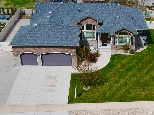 view of front of house featuring a garage, a front yard, fence, stone siding, and concrete driveway
