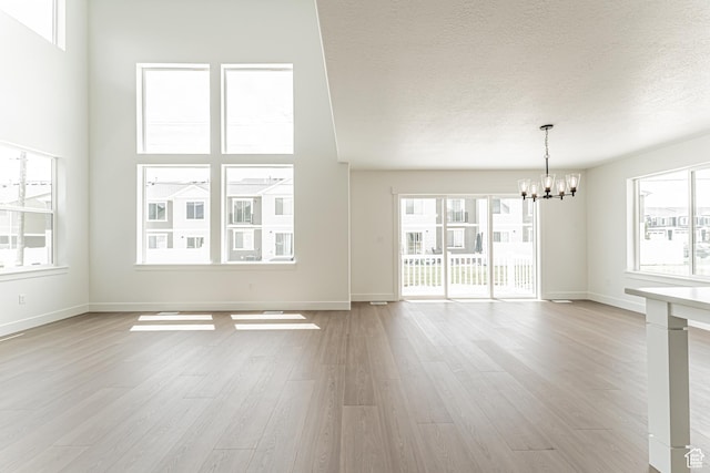 3759 W 950 N Unit 376, Lehi, UT 84043 - unfurnished living room featuring a chandelier, light wood-type flooring, healthy amount of natural light, and a textured ceiling