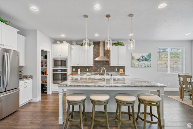 15097 S Cantle Dr, Bluffdale, UT 84065 - kitchen featuring stainless steel appliances, wall chimney range hood, dark wood-style flooring, backsplash, and recessed lighting