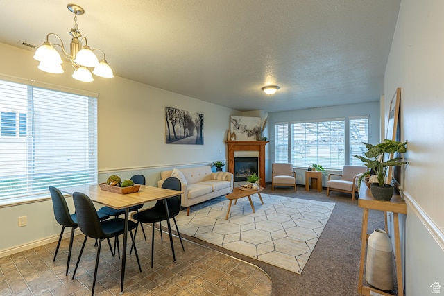 275 W 260 N, Hyde Park, UT 84318 - carpeted dining space with a textured ceiling, visible vents, a chandelier, baseboards, and a glass covered fireplace