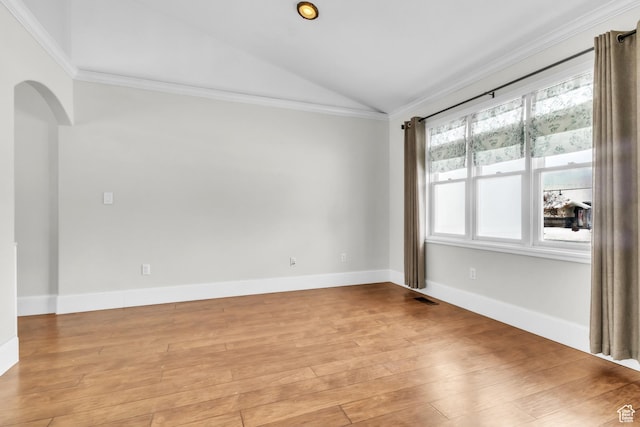 spare room featuring vaulted ceiling, crown molding, light wood finished floors, visible vents, and arched walkways