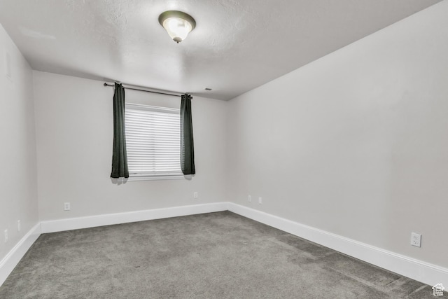 carpeted empty room with baseboards and a textured ceiling