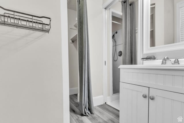 full bathroom with baseboards, wood finished floors, and vanity