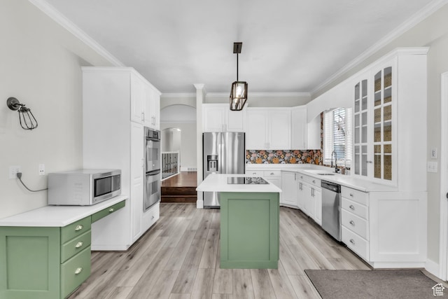 kitchen with stainless steel appliances, arched walkways, white cabinetry, a sink, and green cabinetry