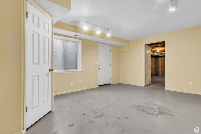 unfurnished bedroom with rail lighting, concrete flooring, baseboards, and visible vents
