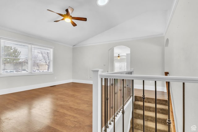 interior space with crown molding, baseboards, wood finished floors, a ceiling fan, and vaulted ceiling