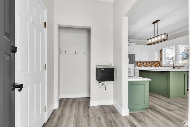 interior space with light wood finished floors, green cabinetry, decorative backsplash, and white cabinetry